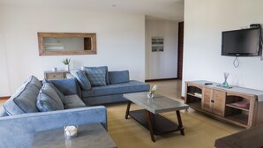 A modern living room with a sofa, two coffee tables, a TV, and a wooden cabinet.