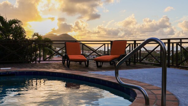 A poolside area with two orange lounge chairs and a metal pool ladder.