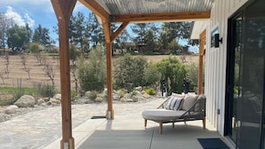 A covered patio with a ceiling fan, a glass table, and two blue chairs. - Hidden Hacienda King Room with Garden View (Temecula)