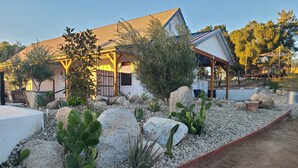 A modern house with a patio area featuring a rock garden with cacti and succulents, a wooden deck, and a covered outdoor seating area. - Hidden Hacienda King Room with Garden View (Temecula)