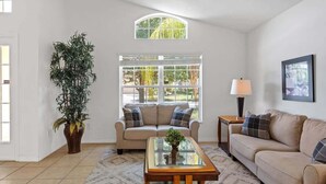 A living room with a sofa, a coffee table, a lamp, and a large window.