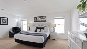 A modern bedroom with a large bed, bedside tables, a dresser, and a painting on the wall.