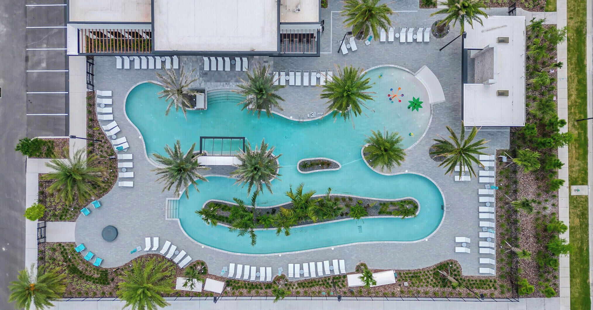 Luchtbeeld van een resort met een groot zwembad, palmbomen en ligbedden.