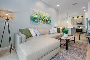 Un salon moderne avec un canapé, une table basse et une lampe sur pied.