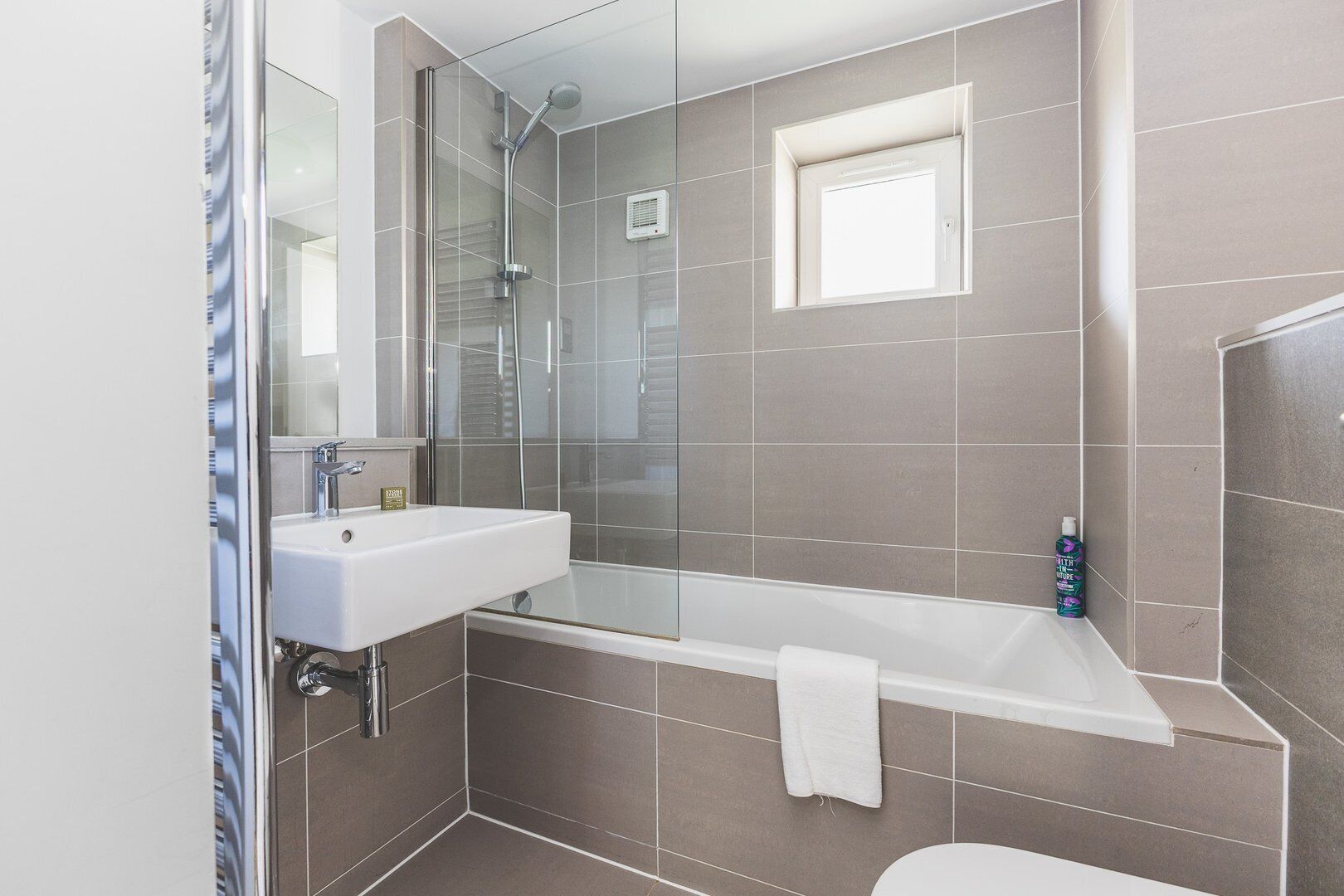 A modern bathroom with a glass-enclosed shower, a white sink, and a bathtub.