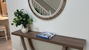 A wooden console table with a mirror above it, a potted plant, and a book titled "Living with BLUE & WHITE". - Last Minute Disney! Private Pool, Hot Tub & Themed Bedrooms. Book Now! #119785 (Orlando)