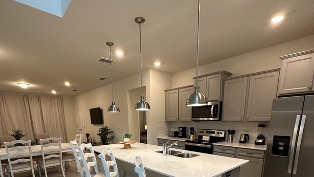A modern kitchen with a central island, white chairs, stainless steel appliances, and pendant lighting. - Last Minute Disney! Private Pool, Hot Tub & Themed Bedrooms. Book Now! #119785 (Orlando)