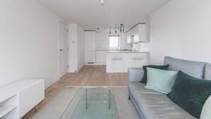 A modern apartment with a kitchenette, a dining area, and a living room with a sofa and cushions.