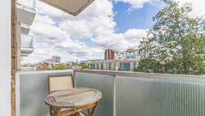 A balcony with a wooden chair and a view of the cityscape.