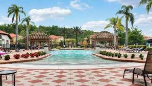 Ein Poolbereich mit zwei Gazebos, Palmen und einer gefliesten Terrasse.