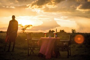 A table set outdoors with a checkered tablecloth, two chairs, and a bottle of wine. - Mara Engai Wilderness Lodge (Nairobi)