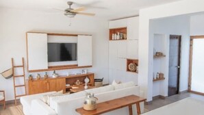 Ein modernes Wohnzimmer mit einem weißen Sofa, einem Holztisch und einem an der Wand montierten Fernseher.