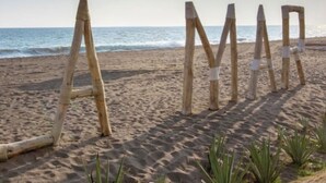 Ein Holzzaun mit den Buchstaben ‚A‘ und ‚M‘ am Strand.