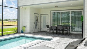 A modern outdoor pool area with a patio, seating, and a view of the landscape.
