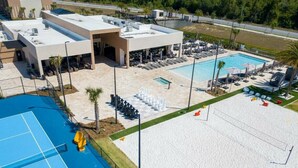 A rooftop pool area with a blue tennis court, lounge chairs, and a pool.