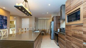 A modern kitchen with a central island, built-in microwave, and stainless steel appliances.
