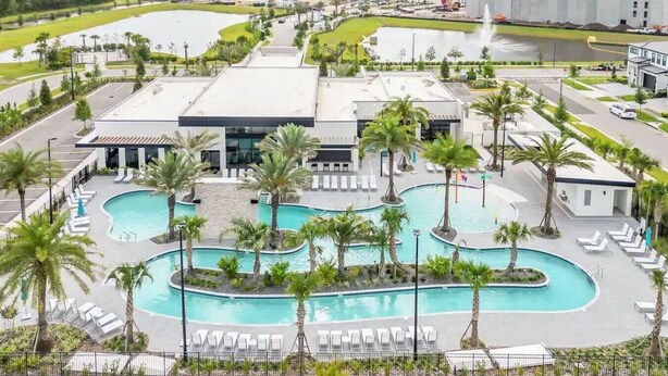 Un hôtel doté d’un grand espace piscine, de palmiers et d’un bâtiment moderne à toit plat.