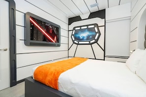 A bedroom with a bed, a wall-mounted TV, and a galaxy-themed wall decoration. - Last Minute Disney Getaway! Private Pool & Themed Bedrooms. Book Now! #150243 (Orlando)
