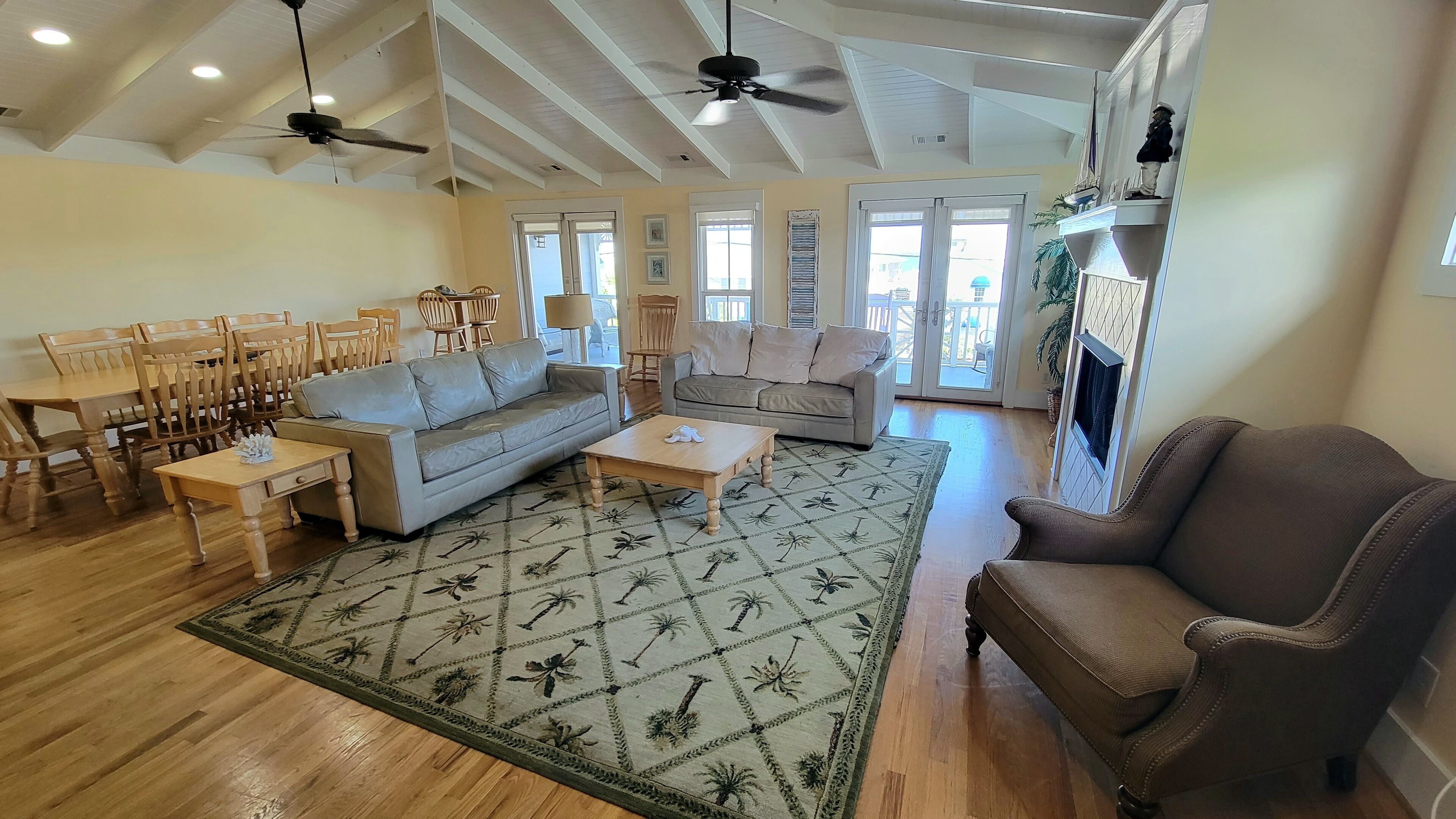 A spacious living room with a sofa, coffee table, and chairs, a dining area with a table and chairs, and a fireplace.