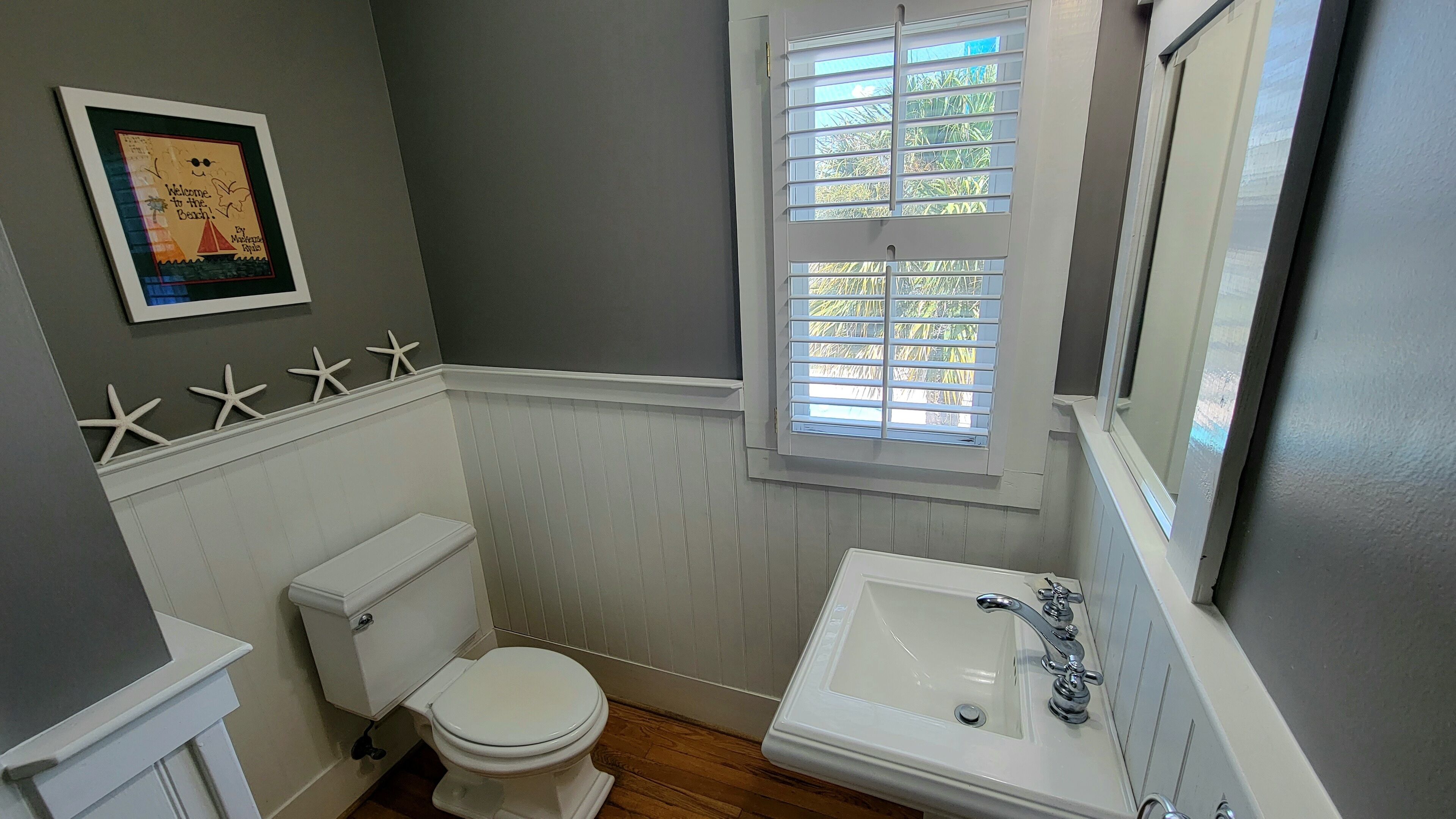 A bathroom with a toilet, sink, and window with blinds.