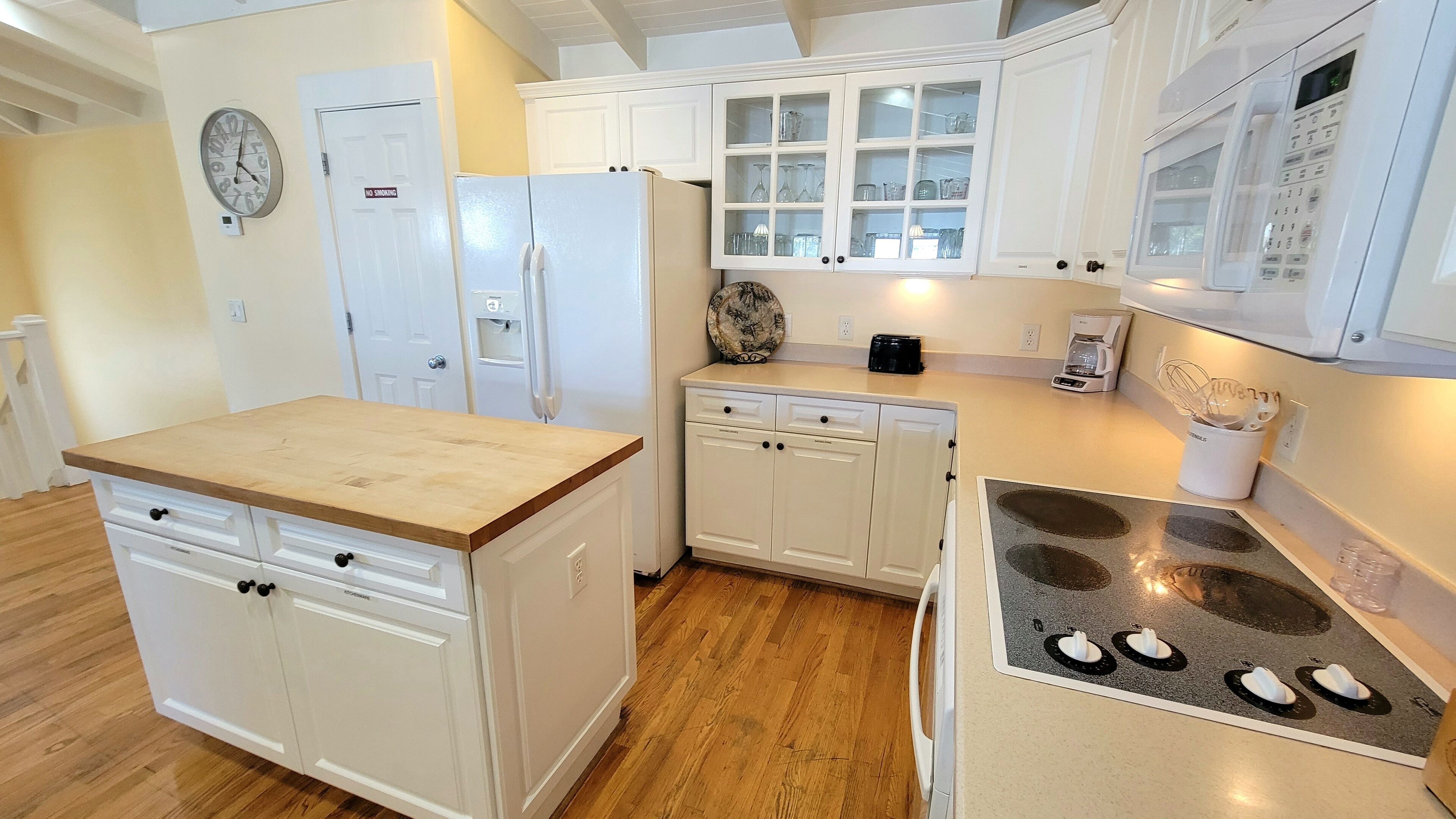 A kitchen with white cabinets, a refrigerator, a stove, and a microwave.