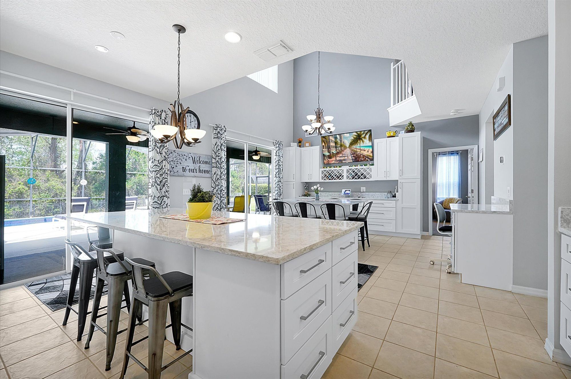 A modern kitchen with a large island, bar stools, and a dining area with a view of the outdoors.