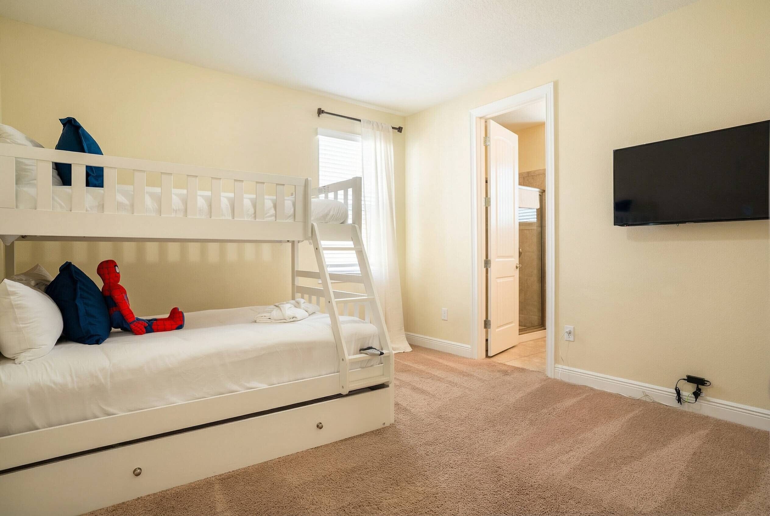 A bunk bed with a ladder, a television mounted on the wall, and a carpeted floor.