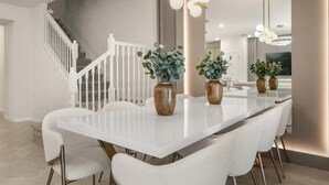 A modern kitchen with a white island, stainless steel appliances, and a staircase leading to another level.