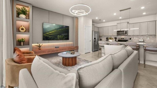 A modern living room with a sofa, coffee table, and a TV mounted on the wall.