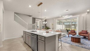A spacious kitchen with a central island, stainless steel appliances, and pendant lighting.