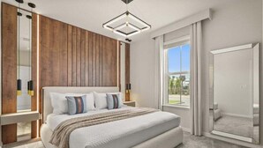A modern bedroom with a large bed, wooden paneling on the walls, a large window, and a mirror.