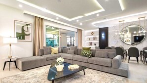A modern living room with a sectional sofa, a glass coffee table, and a large mirror. - Last Minute Disney Getaway! Private Pool & Themed Bedrooms. Book Now! #136701 (Orlando)