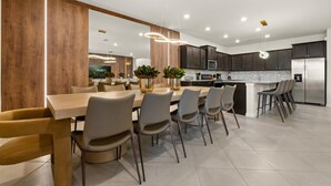 A modern kitchen with a central island, dark cabinetry, and a stainless steel refrigerator.