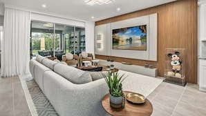 A modern living room with a sectional sofa, a coffee table, and a large painting on the wall. - Last Minute Disney Getaway! Private Pool, Game Room & Themed Bedrooms. Book Now! #147465 (Orlando)
