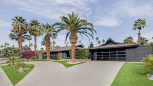 Een modern huis met oprit, palmbomen en garage.