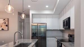 A modern kitchen with granite countertops, stainless steel appliances, and white cabinetry.