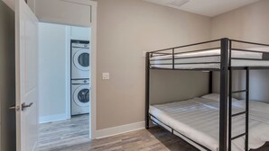 A bunk bed in a room with a washing machine in the background.