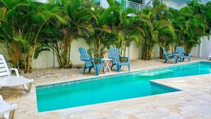 A swimming pool with blue chairs and palm trees.