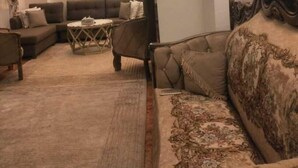 Een gezellige woonkamer met een hoge gewelfde plafond, een gestreept sofa en een kleine ronde tafel.