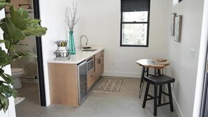 Une cuisine compacte avec un îlot central, un petit coin repas avec des tabourets, une fenêtre et une plante.
