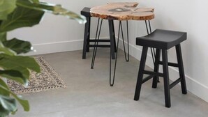 Une petite pièce moderne avec une table ronde en bois et deux tabourets noirs.