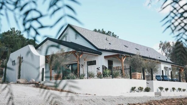 Ein modernes Haus mit einem geneigten Dach, großen Fenstern und einem überdachten Vorbereich.