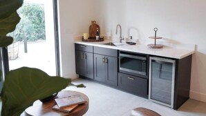 A modern kitchen with dark cabinets, a white countertop, and a built-in dishwasher. - Villa Blanc, Private Individual Suite @ Hidden Hacienda (Temecula)