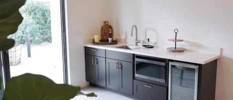 A modern kitchen with dark cabinets, a white countertop, and a built-in dishwasher.