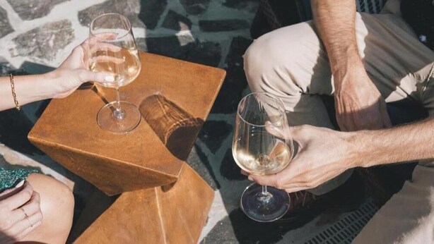 Two people sitting at a table with wine glasses, a book, and a small table. - Villa Blanc, Private Individual Suite @ Hidden Hacienda (Temecula)