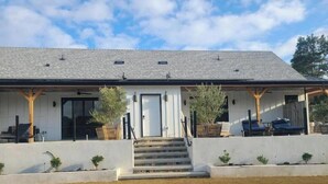 A modern house with a covered porch, a front door, and a staircase leading to the entrance. - Villa Blanc, Private Individual Suite @ Hidden Hacienda (Temecula)