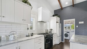 Une cuisine moderne avec des meubles blancs, une cuisinière noire et un lave-linge encastré.