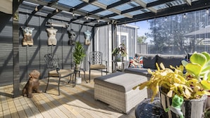Un patio couvert aménagé avec des meubles en osier, des plantes en pot et des objets décoratifs.