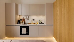 A modern kitchen with a black countertop, stainless steel appliances, and wooden paneling on one wall. - Notting Hill | 1-Bedroom Deluxe Apartment (London)