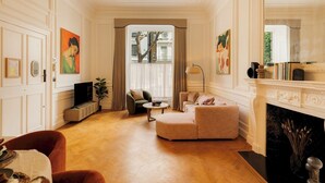 Un salon spacieux doté d’une cheminée, d’un téléviseur et d’un coin repas avec une table mise pour quatre personnes.